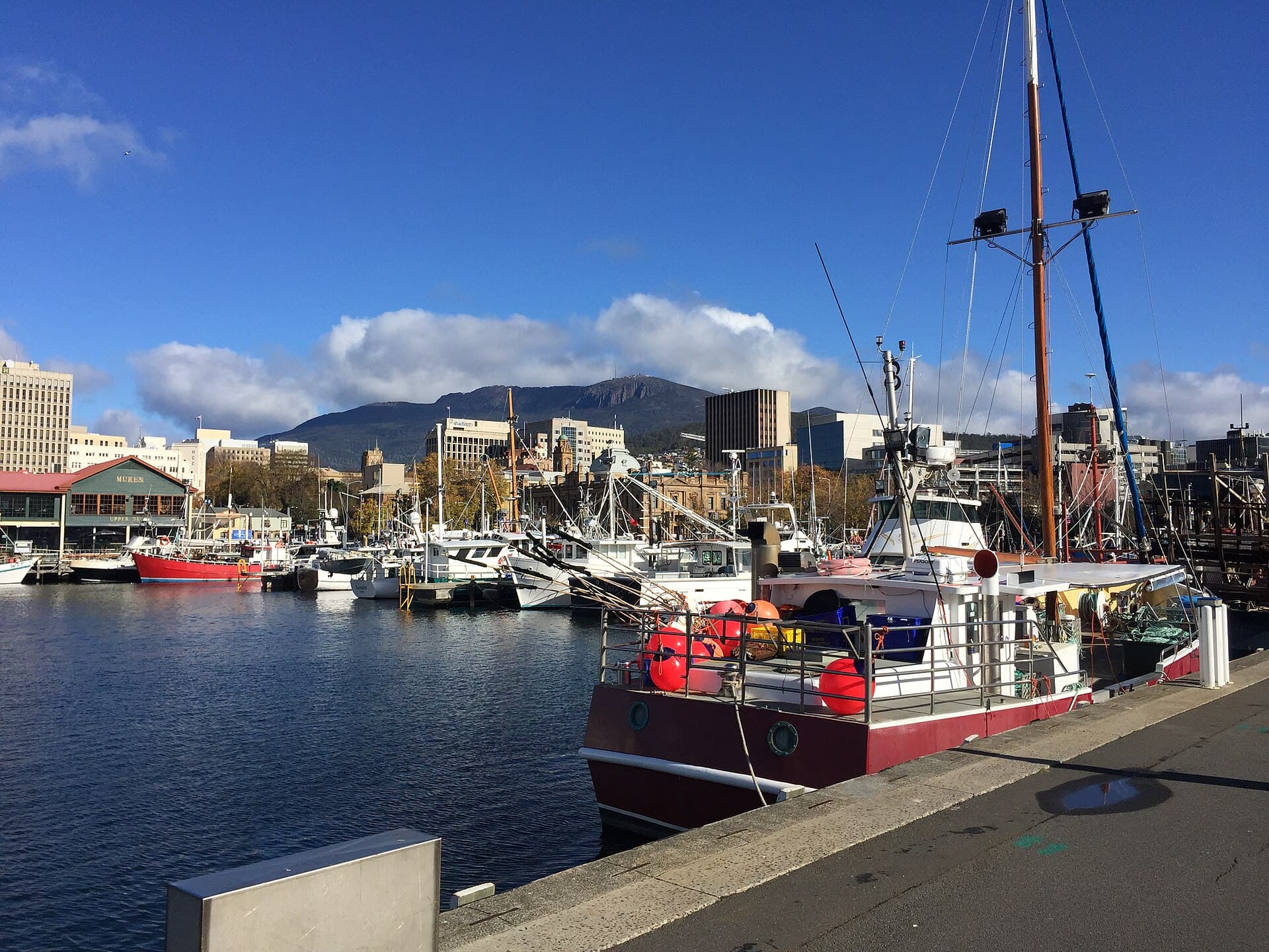 Hobart waterfront warehouses and boats along Sullivan's Cove, with kunanyi / Mount Wellington behind.