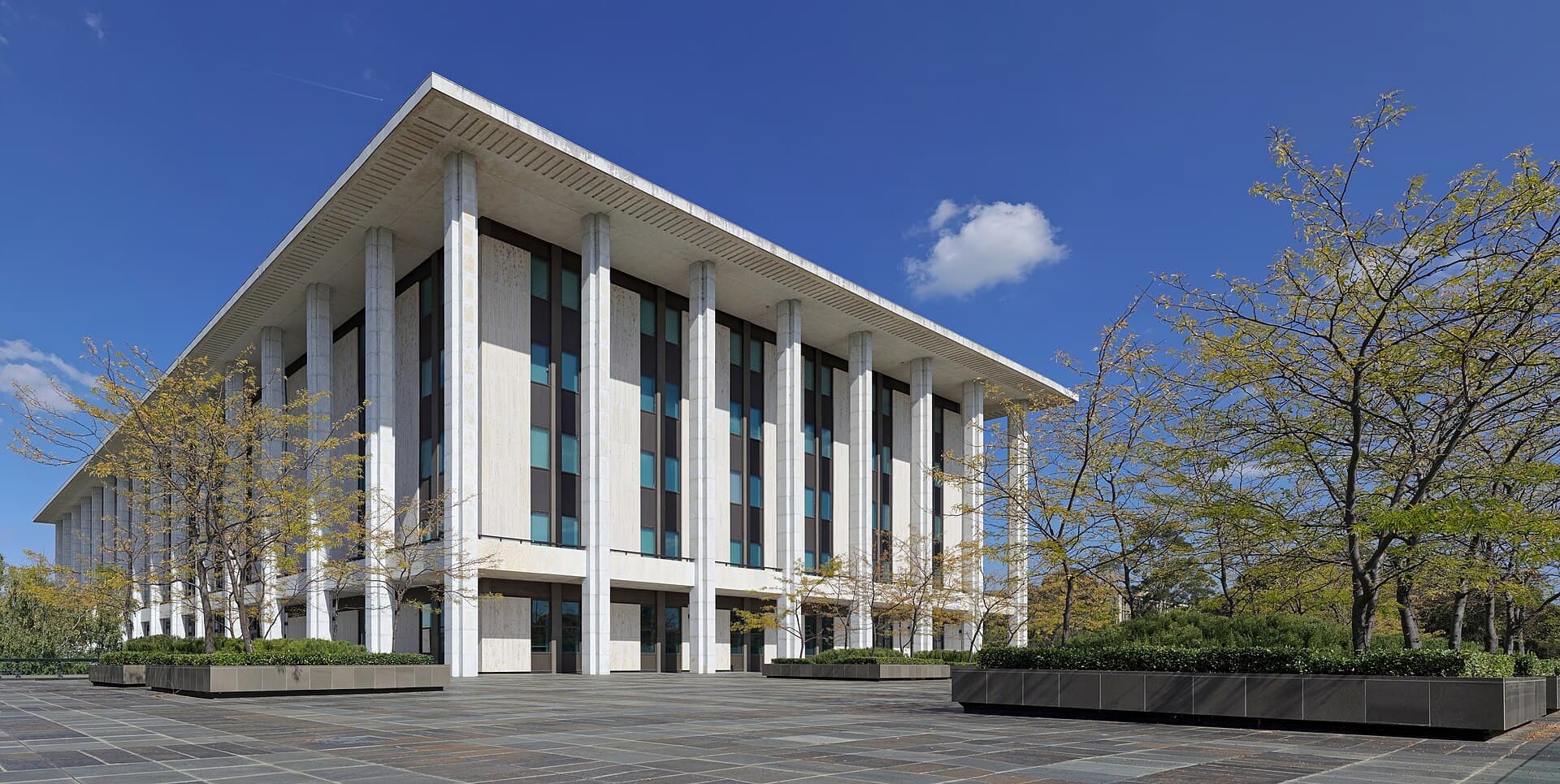 The National Library of Australia in Canberra, its colonnade reflected in still water.