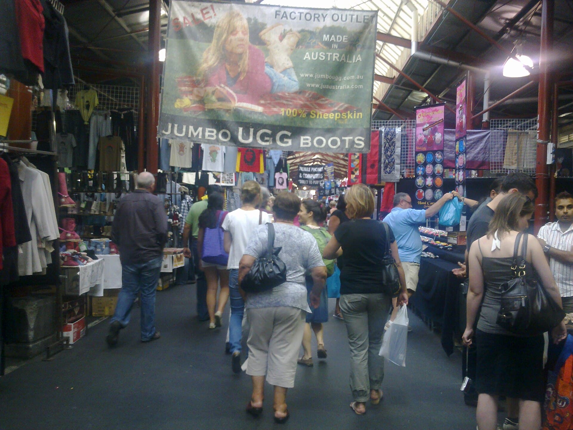 Queen Victoria Market in Melbourne, with shoppers among produce stalls under the historic sheds.